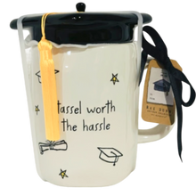 Load image into Gallery viewer, White mug that says tassel worth the hassle and has a black lid that looks like a graduation cap.
