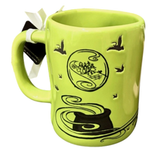 Load image into Gallery viewer, A bright lime green ceramic mug featuring black illustrations of birds, a cauldron, and a circular scene with figures, shown on a plain white background with a hanging tag.
