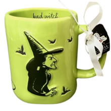 Load image into Gallery viewer, A bright lime green ceramic mug featuring a black design of the Wicked Witch of the West wearing her pointed hat, with small black birds flying around. The inside of the mug is printed with the words 'bad witch' in black script.

