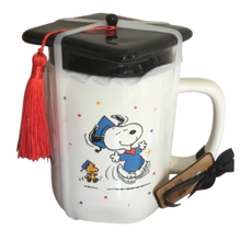 Load image into Gallery viewer, White mug that shows Snoopy and Woodstock graduating with a black lid that looks like a graduation cap.
