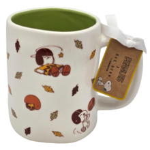 Load image into Gallery viewer, A white ceramic mug featuring Peanuts characters Snoopy and Woodstock in an autumn theme, with a green interior, a white ribbon, and a Peanuts Bat Dunk collectible tag.
