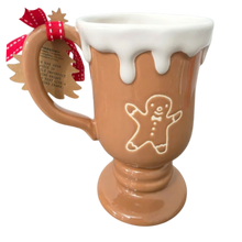 Load image into Gallery viewer, A gingerbread-themed ceramic mug with a brown body, white dripping icing at the top, and an embossed gingerbread man on the front. The handle has a red-and-white polka dot ribbon bow with a hanging tag.
