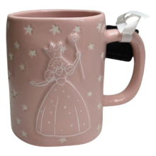 Load image into Gallery viewer, A pink ceramic mug with a white embossed Glinda the good witch design and stars, featuring a white ribbon bow on the handle.
