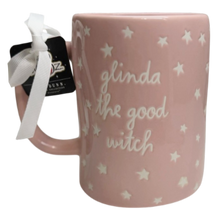 Load image into Gallery viewer, A pink ceramic mug with white embossed stars and the phrase 'glinda the good witch' in white script. The mug has a white ribbon and a black tag attached to the handle, set against a plain white background.
