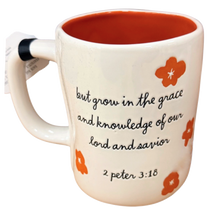 Load image into Gallery viewer, A ceramic coffee mug with a white exterior, orange interior, and black cursive text reading 'but grow in the grace and knowledge of our lord and savior 2 peter 3:18' decorated with orange flower motifs.
