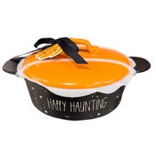 Load image into Gallery viewer, A Halloween-themed dish with a black exterior decorated with white stars and the words 'HAPPY HAUNTING,' topped with a bright orange lid and a black ribbon with a small orange tag, shown on a plain white background.
