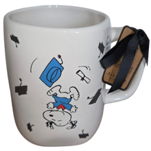 Load image into Gallery viewer, White mug with Snoopy cartoon character in a graduation gown jumping upside down on a white background.
