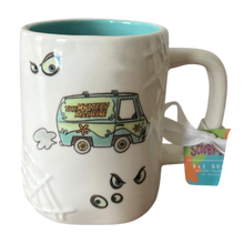 Load image into Gallery viewer, A white ceramic mug featuring a textured design of the Mystery Machine van with cartoon eyes and webbed lines, a turquoise interior, and a hanging tag that reads 'Scooby Doo'.
