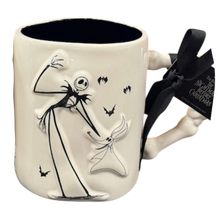 Load image into Gallery viewer, A ceramic mug featuring a sculpted depiction of Jack Skellington and Zero from The Nightmare Before Christmas, with a black ribbon bow tied to the handle. The mug is off-white with black details, and the ribbon tag reads 'The Nightmare Before Christmas'.
