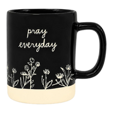 Load image into Gallery viewer, A glossy black ceramic mug with a cream-colored bottom half, featuring the phrase 'pray everyday' in white script and delicate white wildflower illustrations around the lower section.
