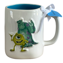 Load image into Gallery viewer, A white ceramic mug featuring raised 3D characters from Monsters Inc., with a blue interior, a white ribbon, and a blue hang tag.
