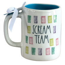 Load image into Gallery viewer, A white ceramic mug with a blue interior, featuring the words 'SCREAM TEAM' in black script and colorful watercolor-style door illustrations. A white ribbon is tied to the handle.
