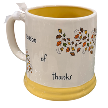Load image into Gallery viewer, A ceramic mug with a white exterior, yellow interior and base, decorated with autumn leaves and the words 'season of thanks'.
