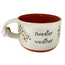 Load image into Gallery viewer, A ceramic mug with a white exterior, orange interior and base, and black text reading 'sweater weather' alongside autumn leaf illustrations.
