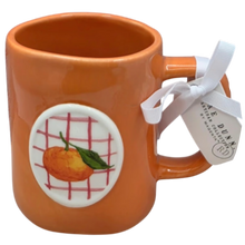 Load image into Gallery viewer, Orange mug with a decorative label featuring an orange and green leaf.
