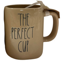 Load image into Gallery viewer, A beige ceramic mug with the phrase 'THE PERFECT CUP' printed in black lettering, featuring a white ribbon tied in a bow around the handle, set against a plain white background.
