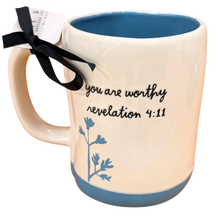 Load image into Gallery viewer, An off-white ceramic mug with a blue interior and base, featuring the printed text 'you are worthy revelation 4:11' and a blue floral design. A black ribbon and white tag are tied to the handle.
