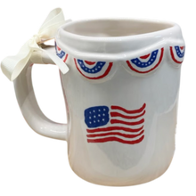 Load image into Gallery viewer, White mug with American flag design and decorative ribbons on a white background

