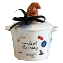 Load image into Gallery viewer, A white ceramic Harry Potter-themed pot with the text 'wands at the ready' and small wand and owl illustrations, topped with a brown Sorting Hat and a black ribbon bow, on a white background.
