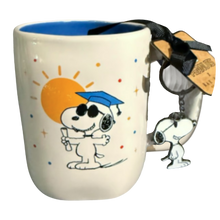 Load image into Gallery viewer, White mug with blue inside that shows an image of Snoopy holding a diploma and wearing a graduation cap.
