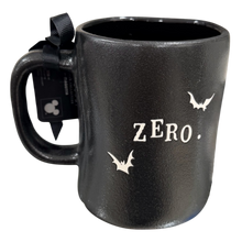 Load image into Gallery viewer, A black textured ceramic mug featuring the word 'ZERO.' and three bat silhouettes in white, along with a black ribbon and hangtag.
